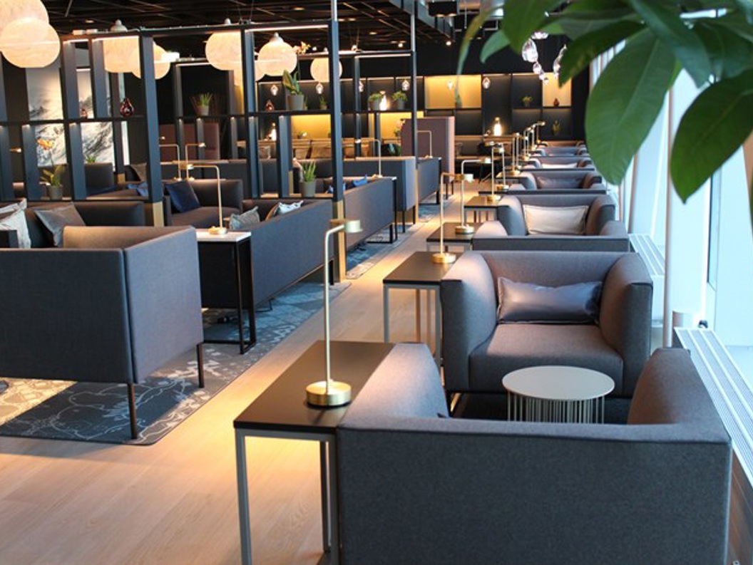 Moderne og elegant lounge med komfortable grå sofaer, små bordlamper, og dekorative elementer, designet for avslapning og sosial interaksjon.